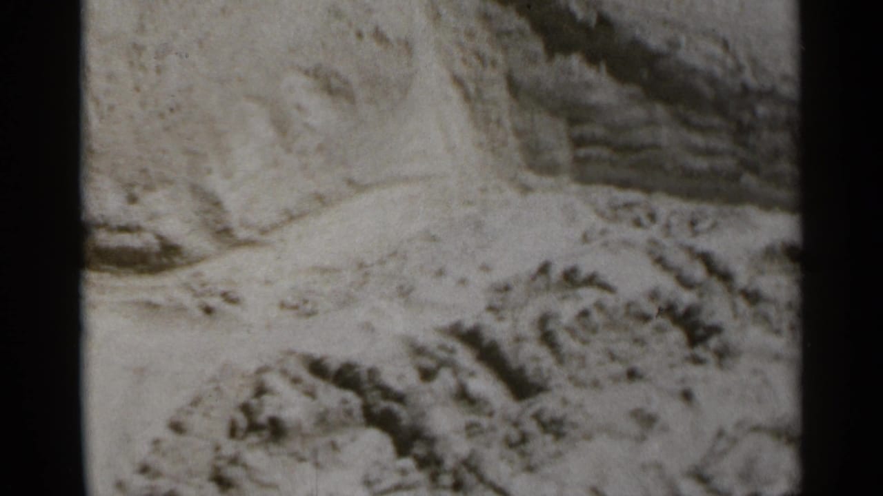 Close 8mm frame of textured beach sand, with a hand partly visible near the edge during the New York boardwalk outing.