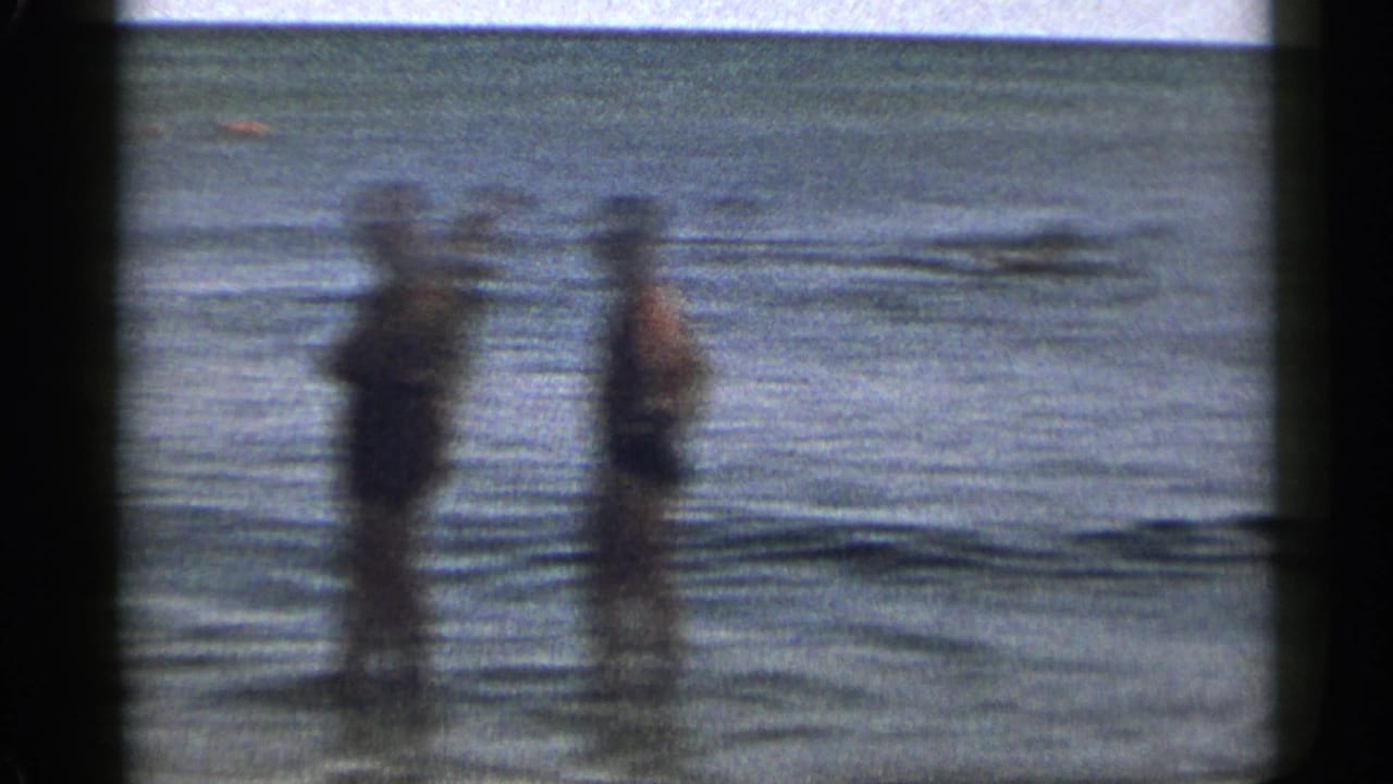 Two blurred adults stand in shallow water facing the camera.