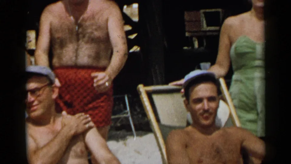 Adults in midcentury swimwear gather near lounge chairs in a 1954 New York beach-party home movie.