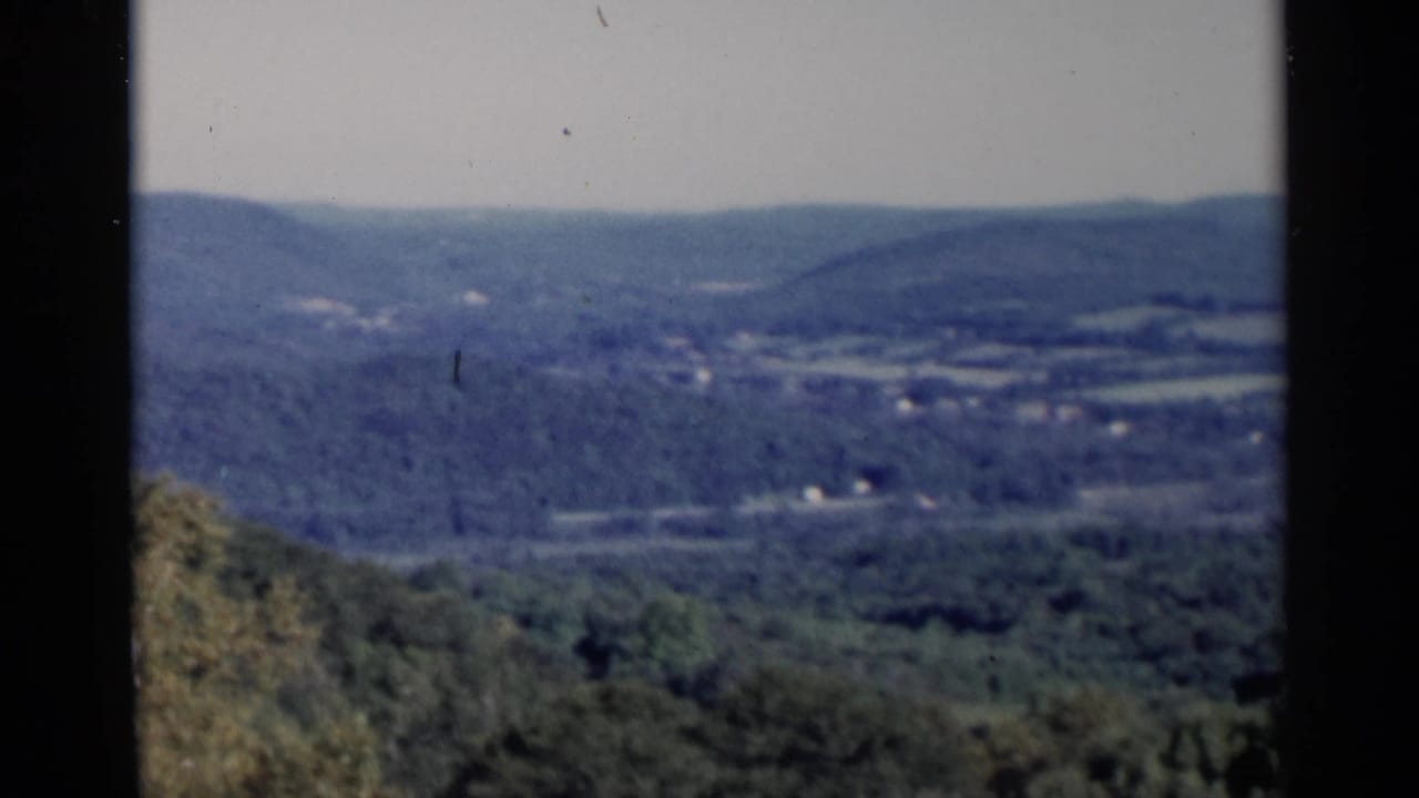 Soft 8mm view over wooded hills and a distant rural valley.