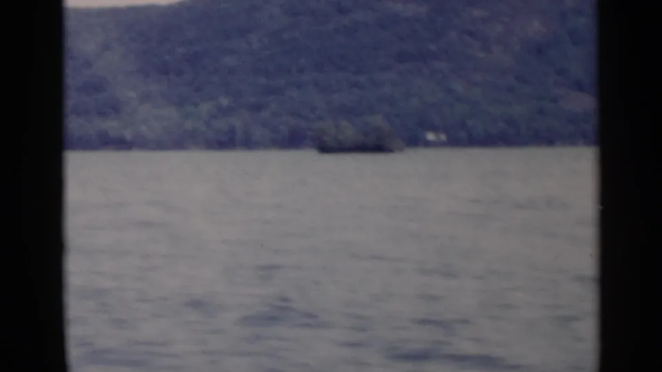 1955 Lake George home-movie frame showing rippled water and dark forested hills beyond the lake.
