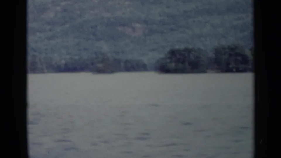 Wide 1955 Lake George view with muted water, distant wooded shoreline, and soft 8mm exposure.