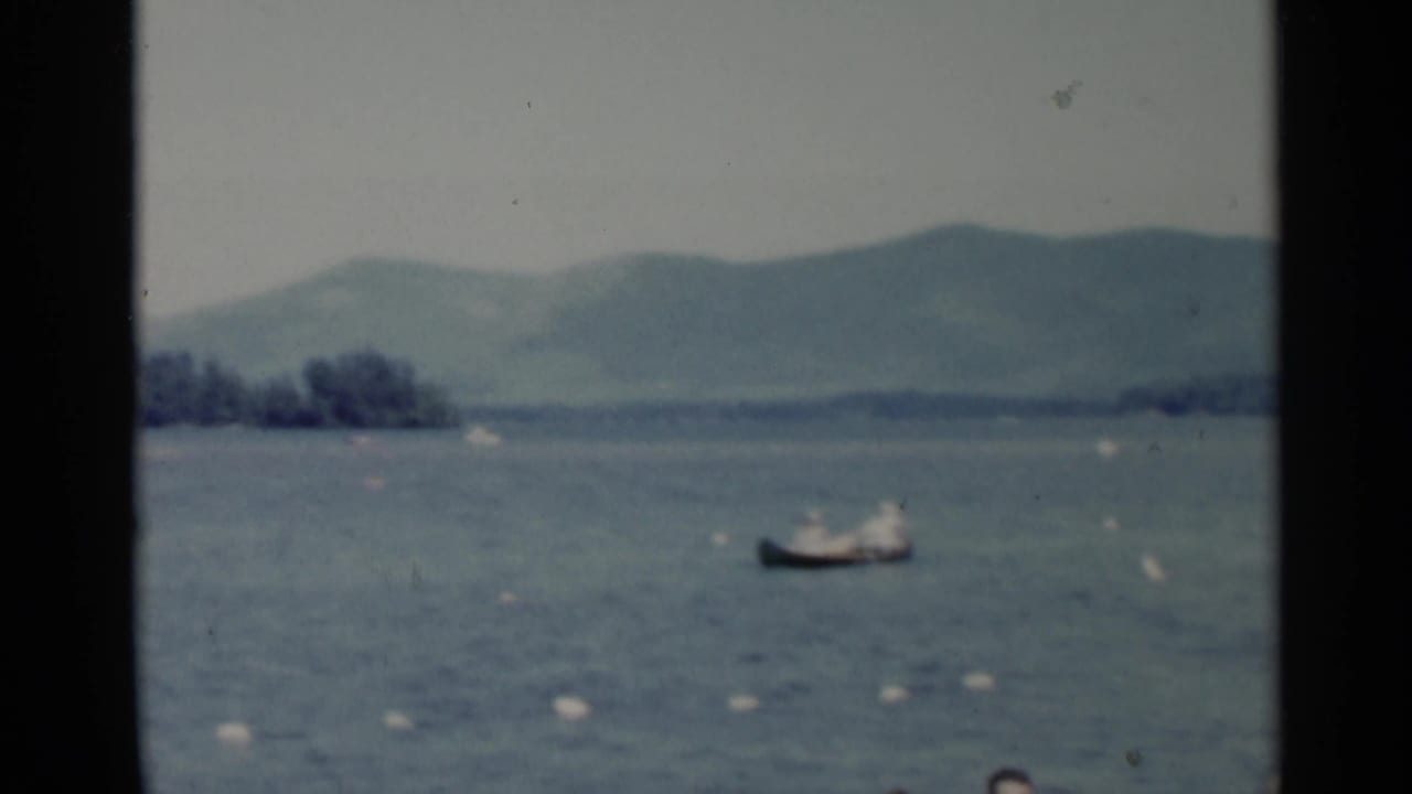 1955 Lake George 8mm frame showing a small boat on open water, distant hills, and visible gate borders from the film scan.
