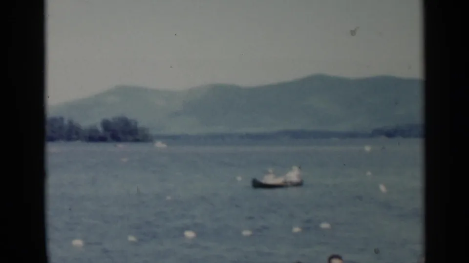 1955 Lake George 8mm frame showing a small boat on open water, distant hills, and visible gate borders from the film scan.