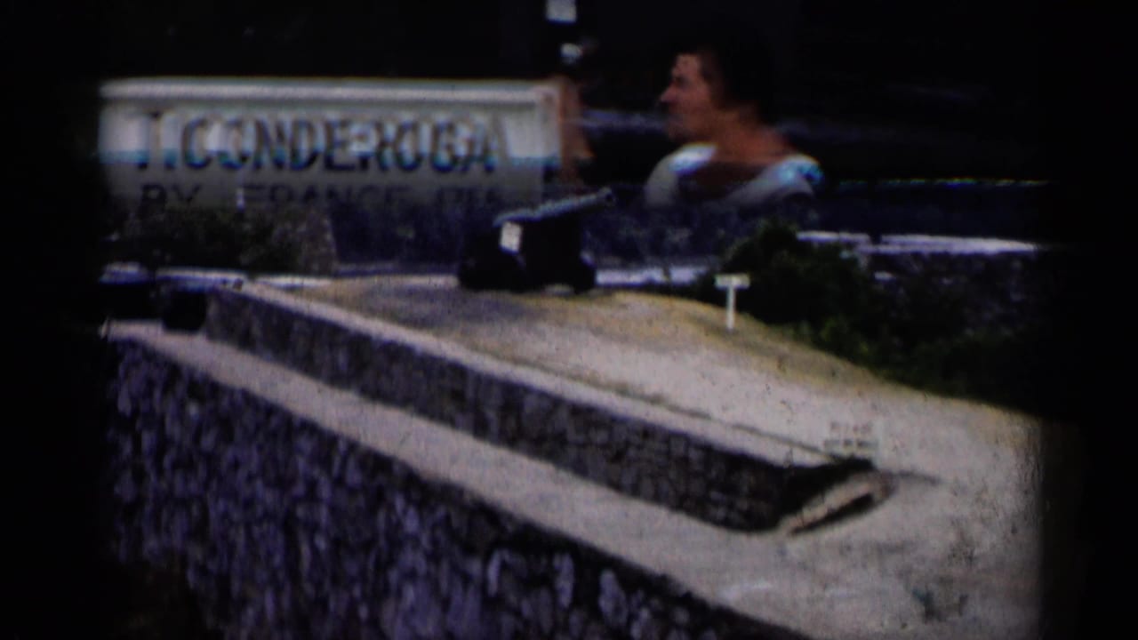 In Lake George-area 1955 home-movie footage, a woman stands by a Ticonderoga sign with a cannon and stone fortifications nearby.
