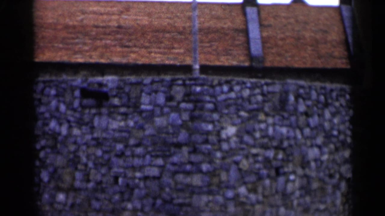 Close view of stone wall beneath a red-tiled roof.