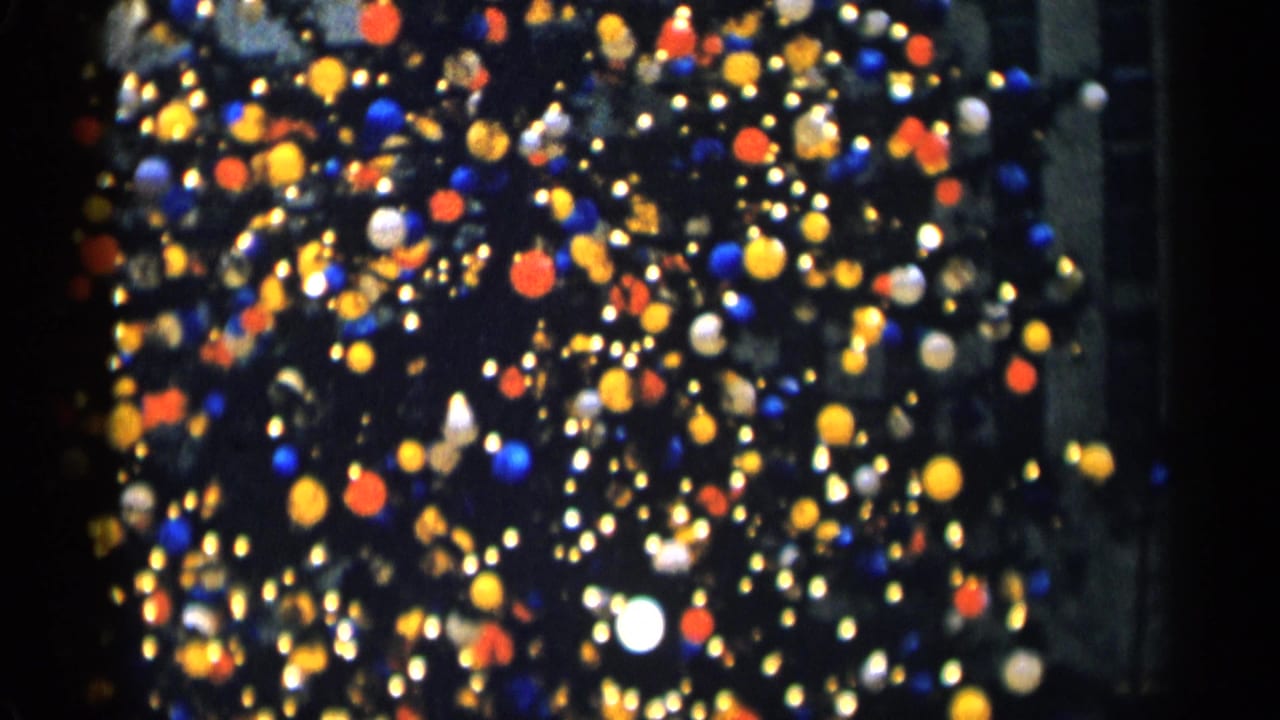 Soft-focus Christmas tree lights and ornaments against a dark urban background.