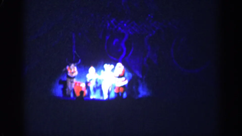 1955 New York City home-movie frame showing Christmas-costumed performers on a dark stage with blue spotlighting.