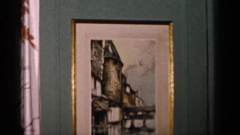 A framed castle picture on a green wall, with a dark vertical opening or shadow at left in the 1955 interior footage.