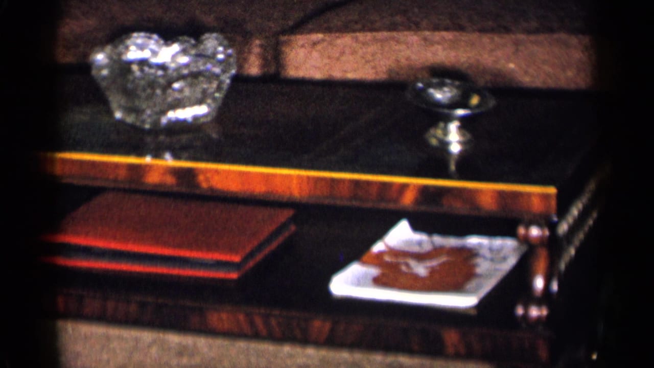 Glass-topped coffee table with crystal bowl, small silver dish, red book, and brown couch behind it.