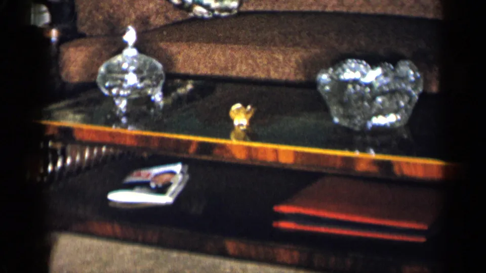 1950s New York City home interior showing a coffee table with crystal serving pieces, a magazine, and a red book below a brown couch.