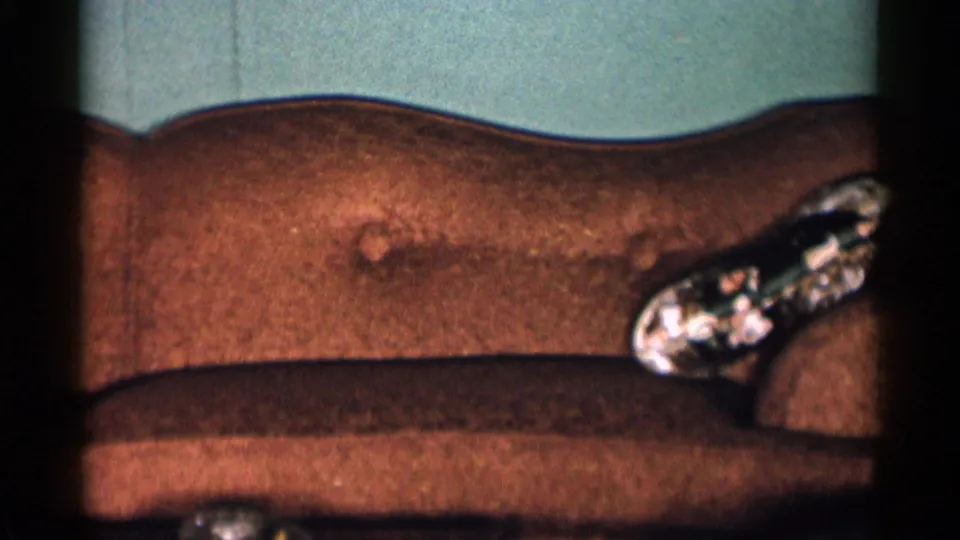 1955 New York City interior frame with a brown sofa, teal wall and patterned glass ashtray on the sofa arm.