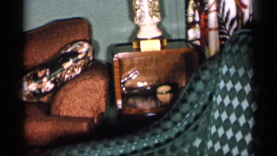 1955 New York City home interior frame showing the sofa, side table, lamp base and patterned fabric near the edge of the shot.