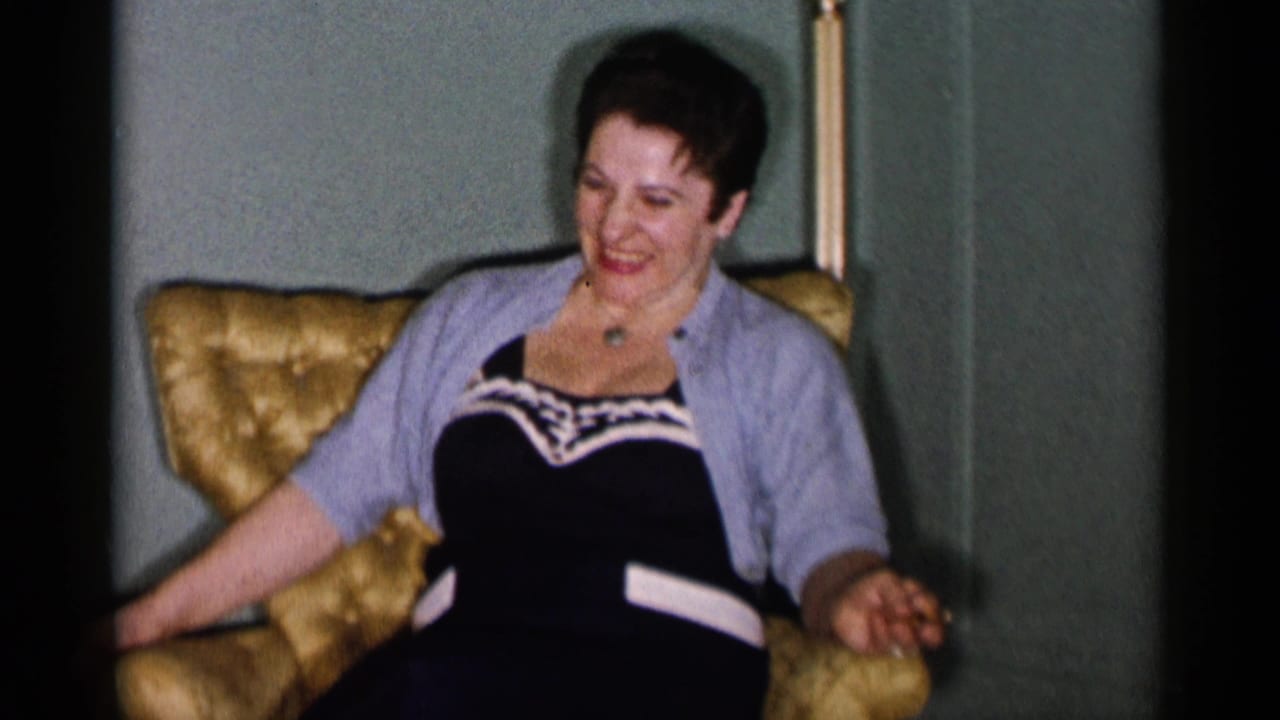 Woman laughing while seated in a gold armchair indoors.