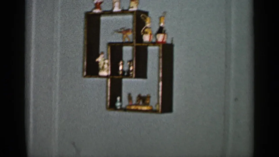 A 1955 New York City home-movie frame centers on a geometric wall shelf with figurines, bottles, and small keepsakes.
