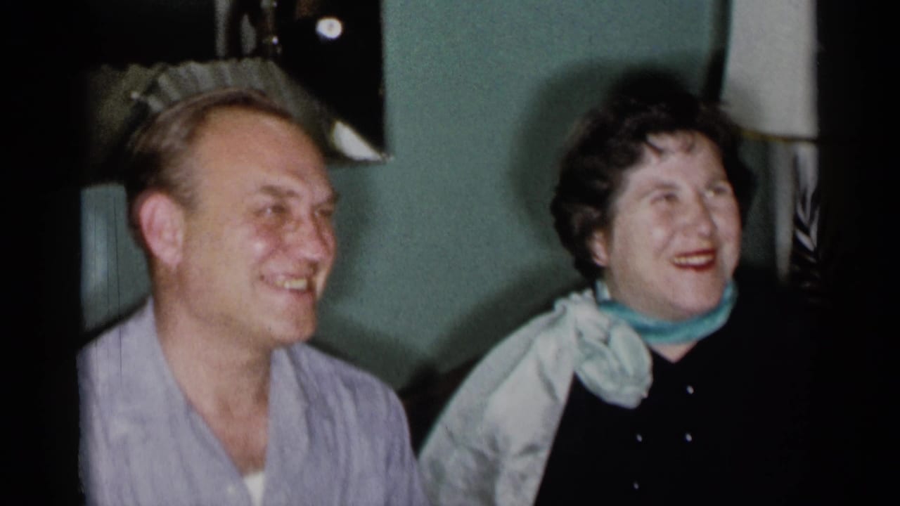 Man and woman seated indoors laughing together in a living room.