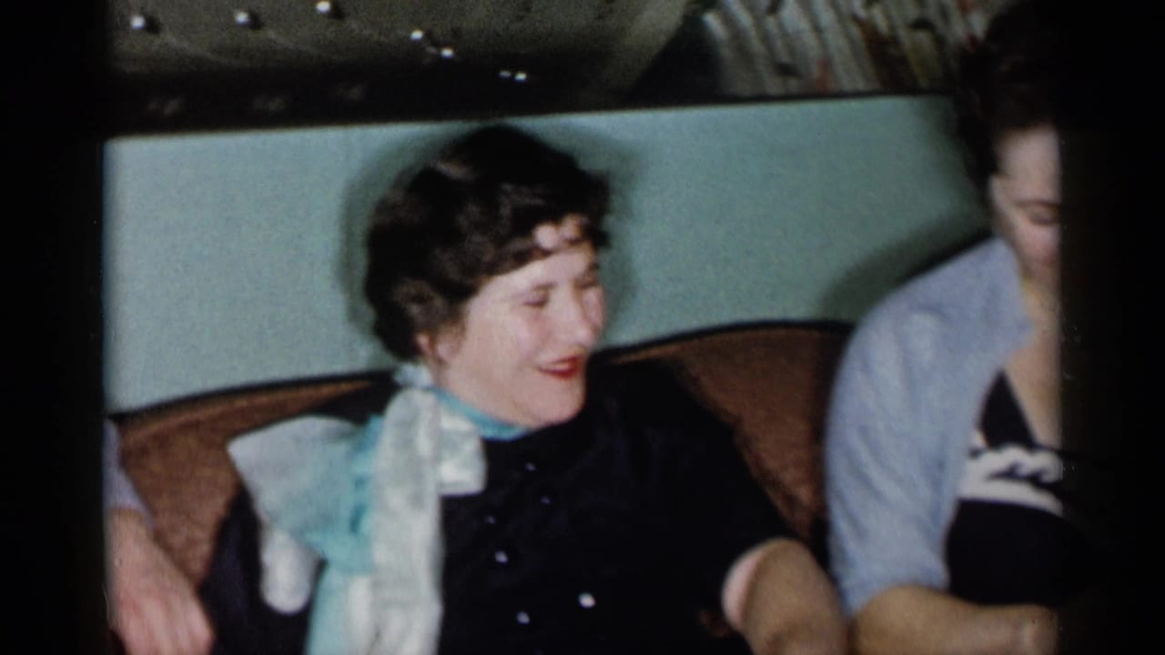 Two women seated on a sofa, one laughing while another is partly visible beside her.
