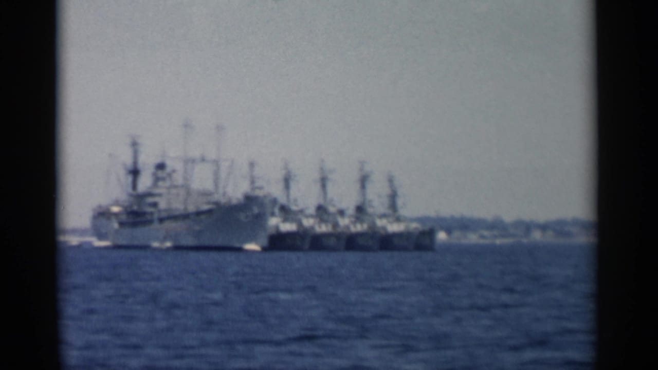 Distant ships anchored across open water under a pale sky.