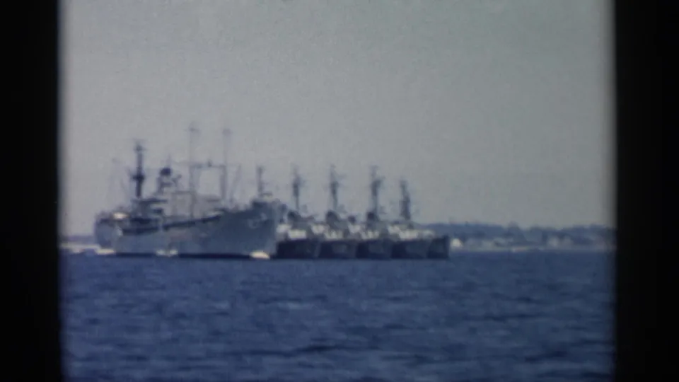 1956 Cape Cod 8mm frame showing a large ship and smaller vessels across blue harbor water.