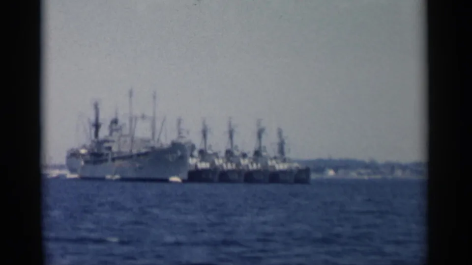 Distant naval-looking vessels anchored in a Cape Cod harbor, filmed on faded 8mm color stock in 1956.