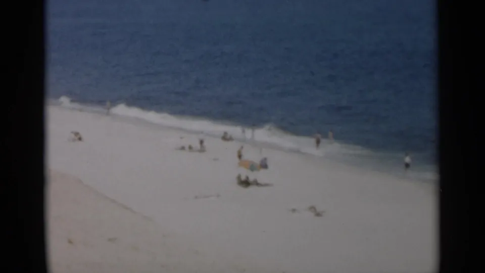 1956 Cape Cod beach footage showing a wide sandy shore, distant visitors, and gentle surf along the waterline.