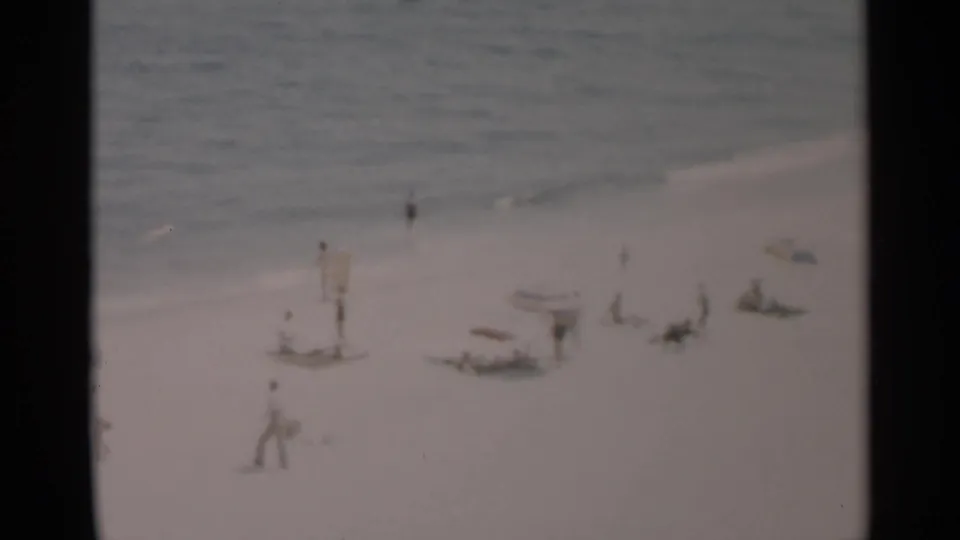 A wider 1956 Cape Cod beach view shows umbrellas, reclining beachgoers, walkers, and a small boat or craft near the water.