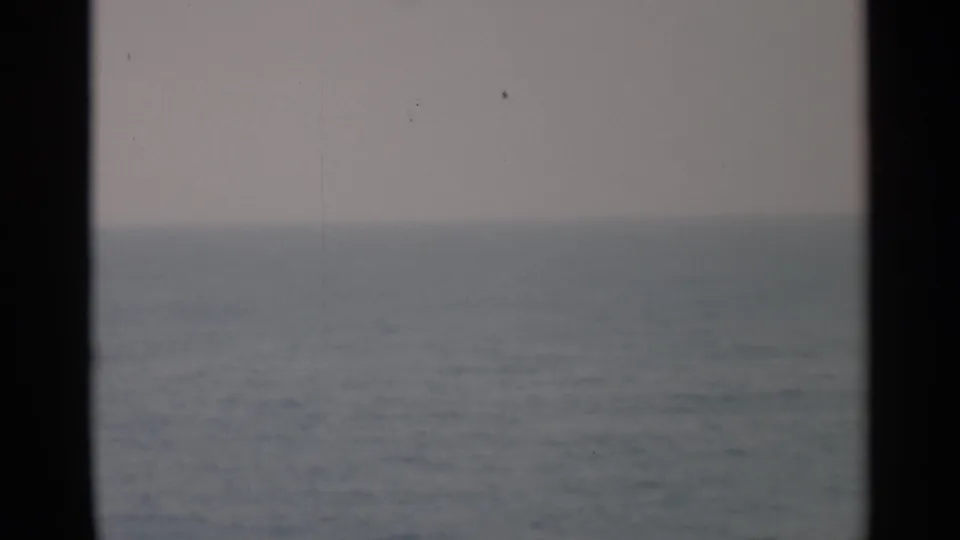 1956 Cape Cod travel footage showing a soft ocean horizon framed by dark ship window or porthole edges.