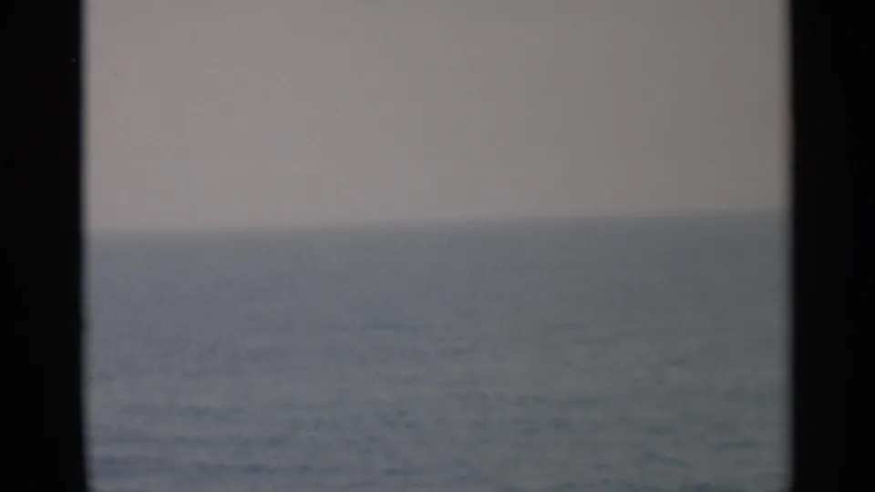 Cape Cod ocean view in 1956 home-movie footage, with soft water tones and dark vessel-window framing.