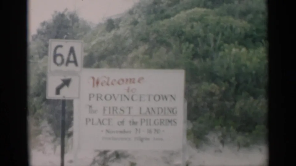 Home-movie frame from Cape Cod showing the Route 6A marker and part of the Provincetown welcome sign, slightly blurred by handheld motion.