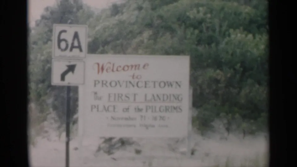 1956 8mm travel frame showing the Provincetown welcome sign, Route 6A marker, and sandy roadside vegetation on Cape Cod.