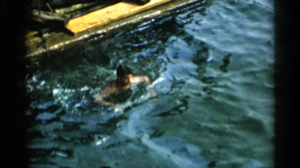 A man swims near the edge of a pool or waterfront area in 1950s Cape Cod home-movie footage.