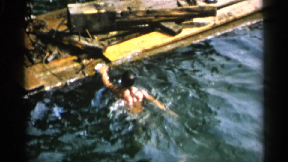 Adult man swims near a wooden dock in Cape Cod home-movie footage from 1956.
