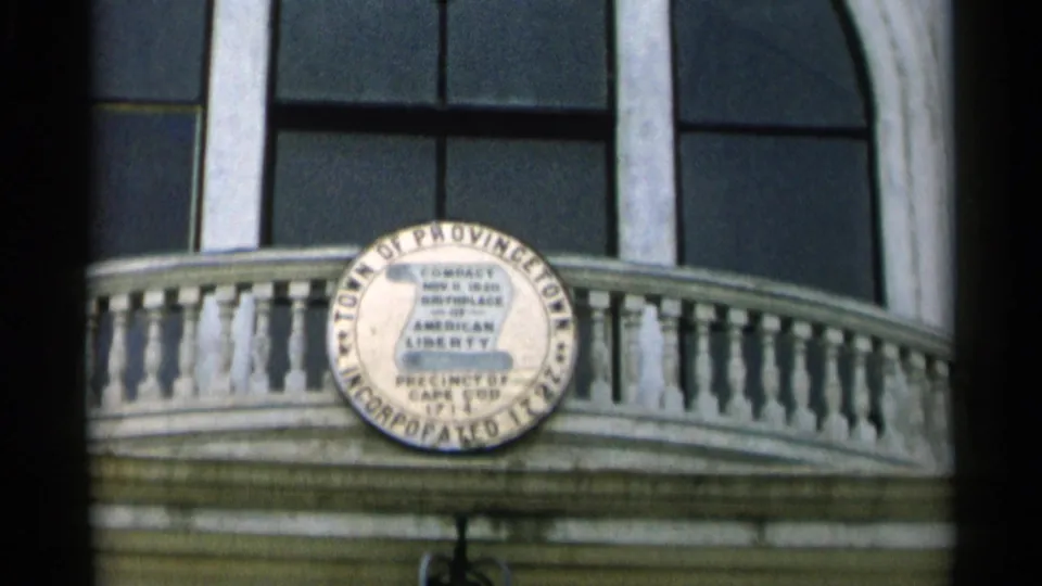 Town of Provincetown seal appears on a building facade with windows and a balcony rail.