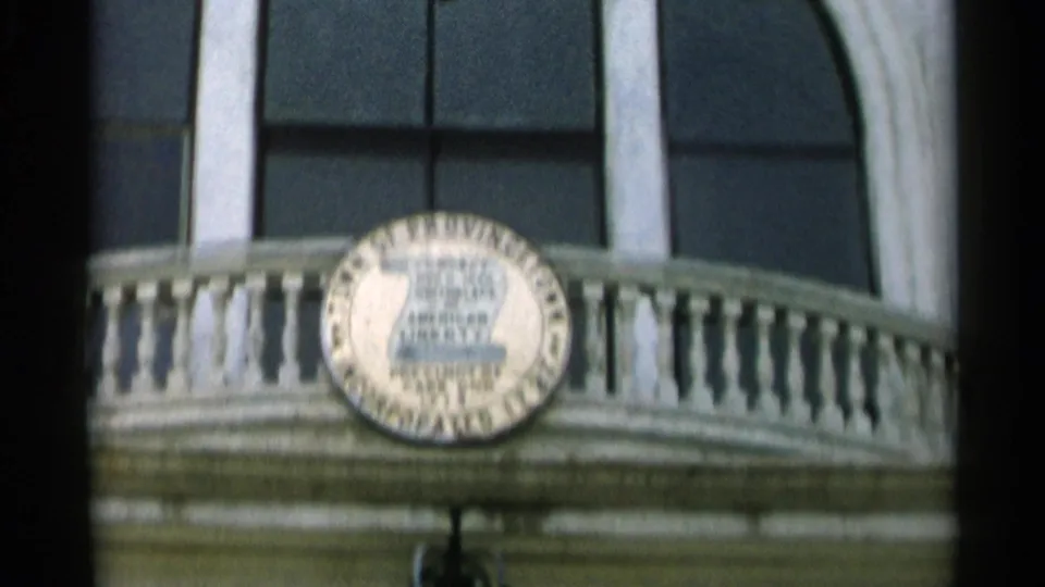 Close 8mm view of the Provincetown town seal centered on a white balcony facade in Cape Cod, Massachusetts.