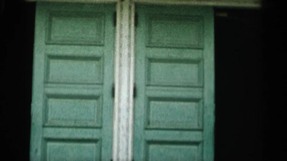 Visitor-shot 8mm frame of a green double door beneath the Provincetown seal and white balcony in Cape Cod.
