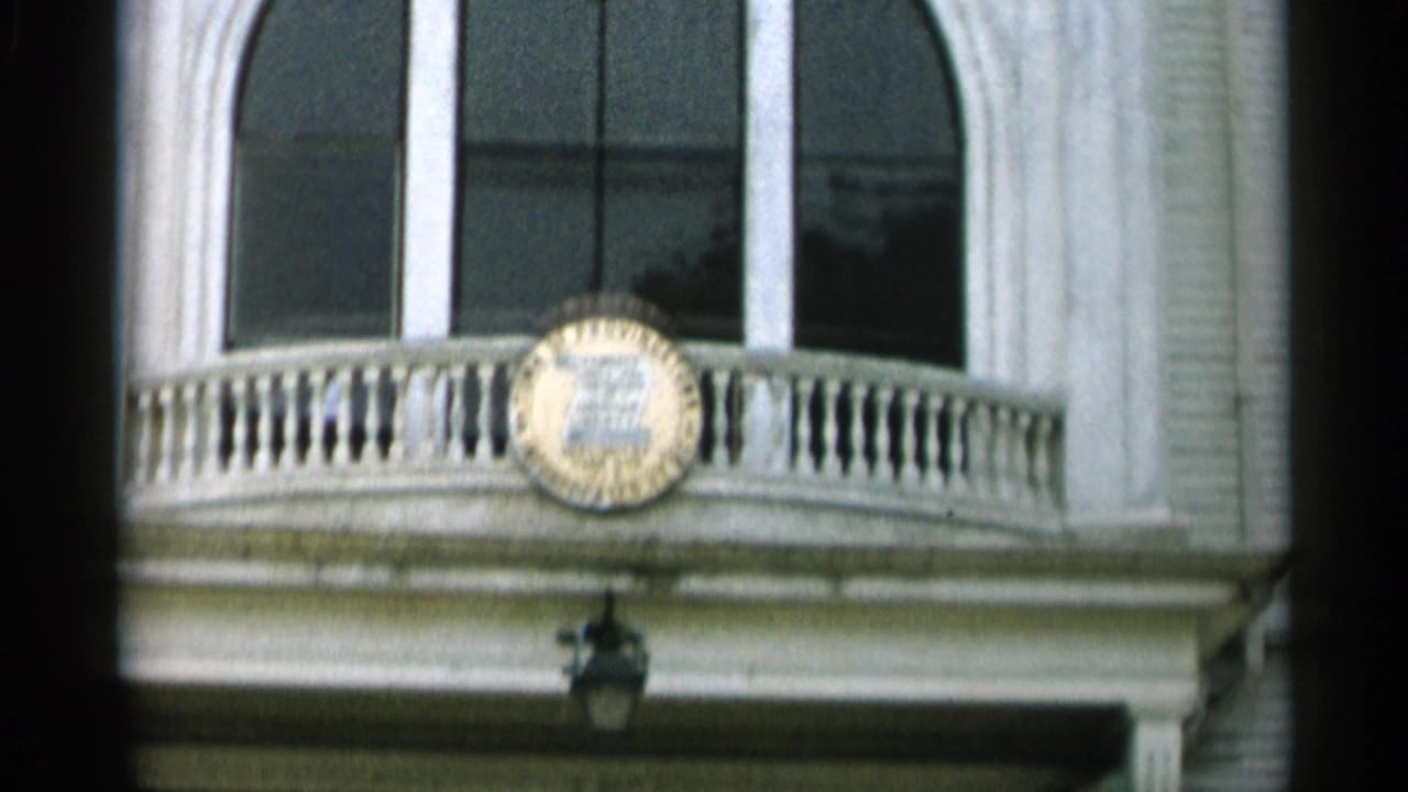Close view of a white building facade with arched windows and a curved balcony.