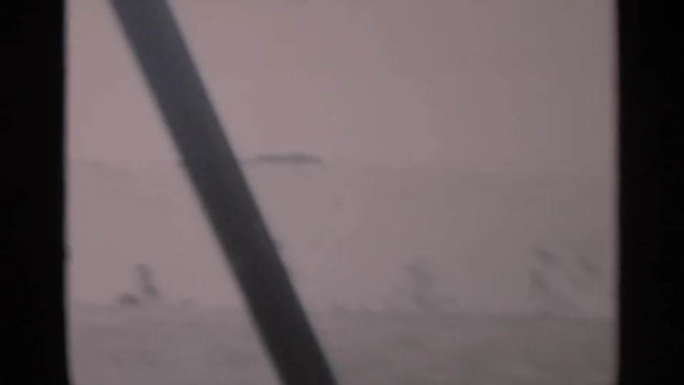 1956 Cape Cod home-movie frame looking through a vehicle window at a soft, muted roadside or horizon view.