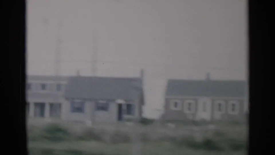 Cape Cod roadside houses appear across a grassy foreground in soft 1956 8mm color footage.