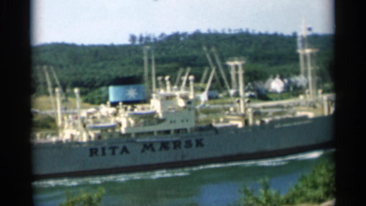 Cargo ship Rita Mærsk passing along a green shoreline waterway.