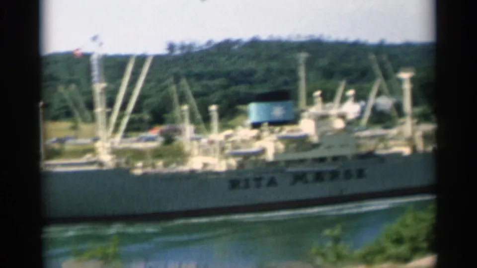 The Rita Mærsk is partially framed by dark 8mm gate edges as it moves along the Cape Cod waterway in bright sun.