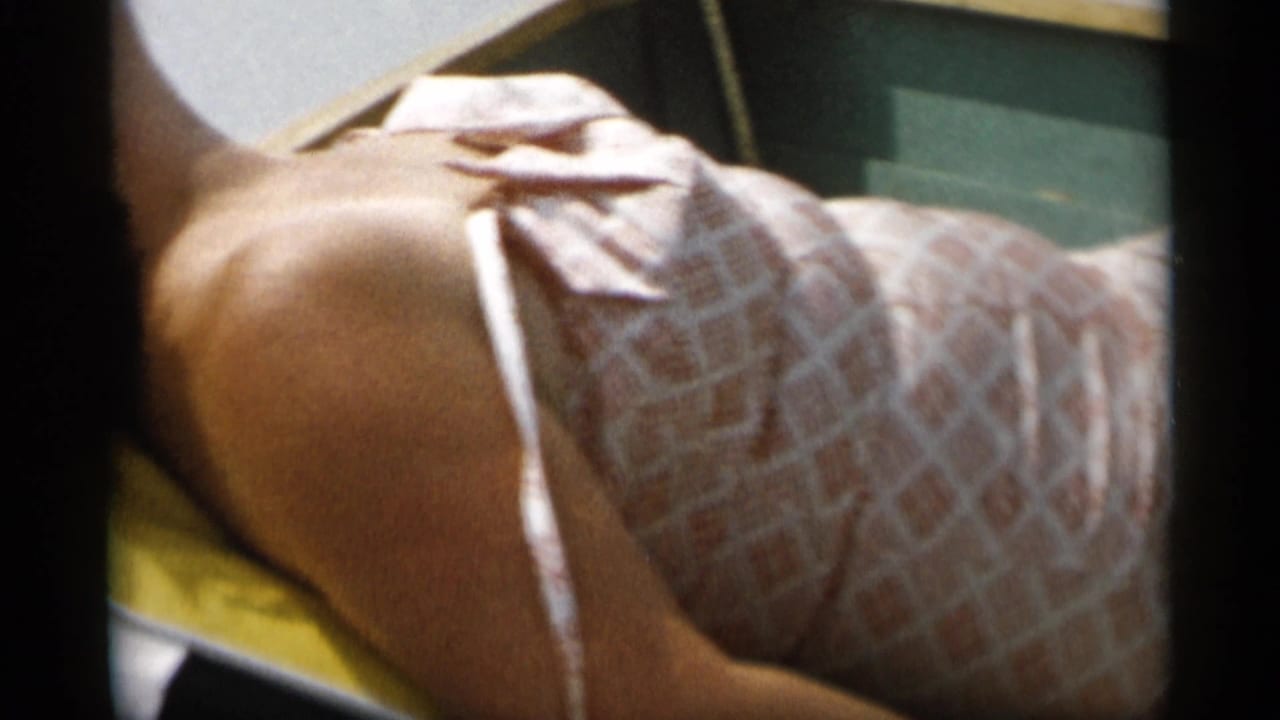 Adult woman reclining on a Cape Cod boat in 1956 footage, wearing a light patterned dress beside a rail and water.