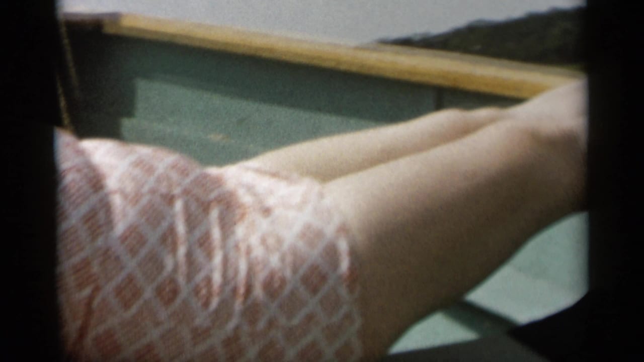 1956 Cape Cod home-movie frame showing a reclining woman on a boat with legs extended near the rail.