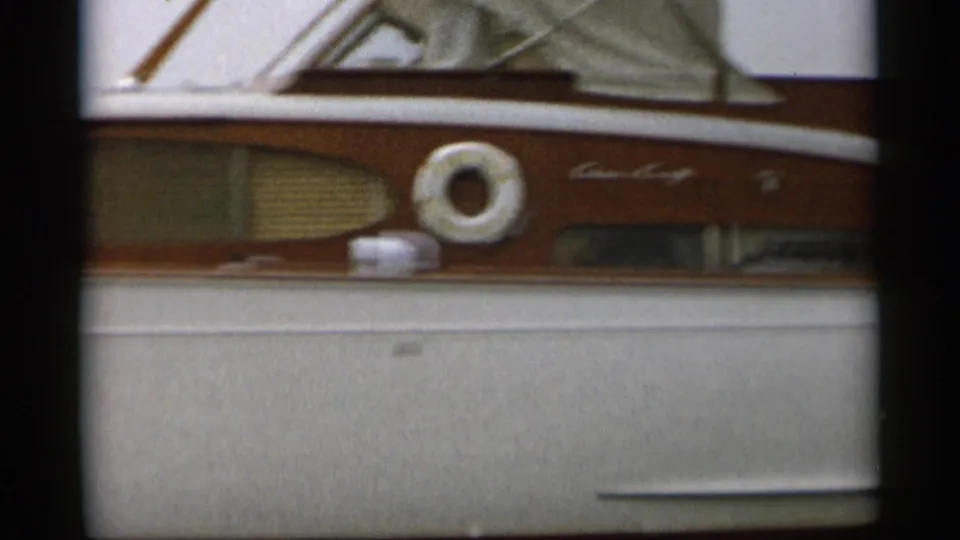 Close 8mm view of the motorboat's wood cabin side, white hull, life ring, and name or maker marking.