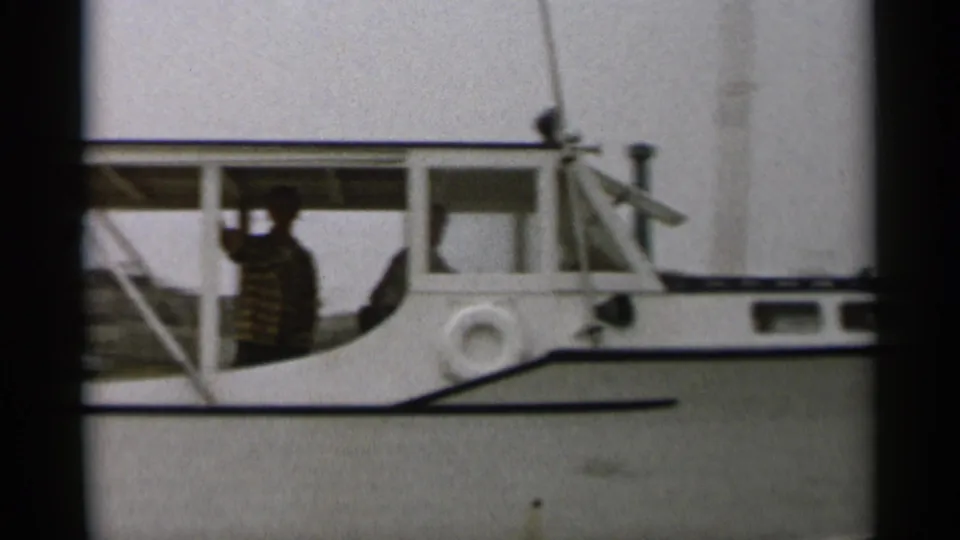 Close 1956 Cape Cod view of the boat cabin, with a passenger visible through the open side area and registration marking partly seen.