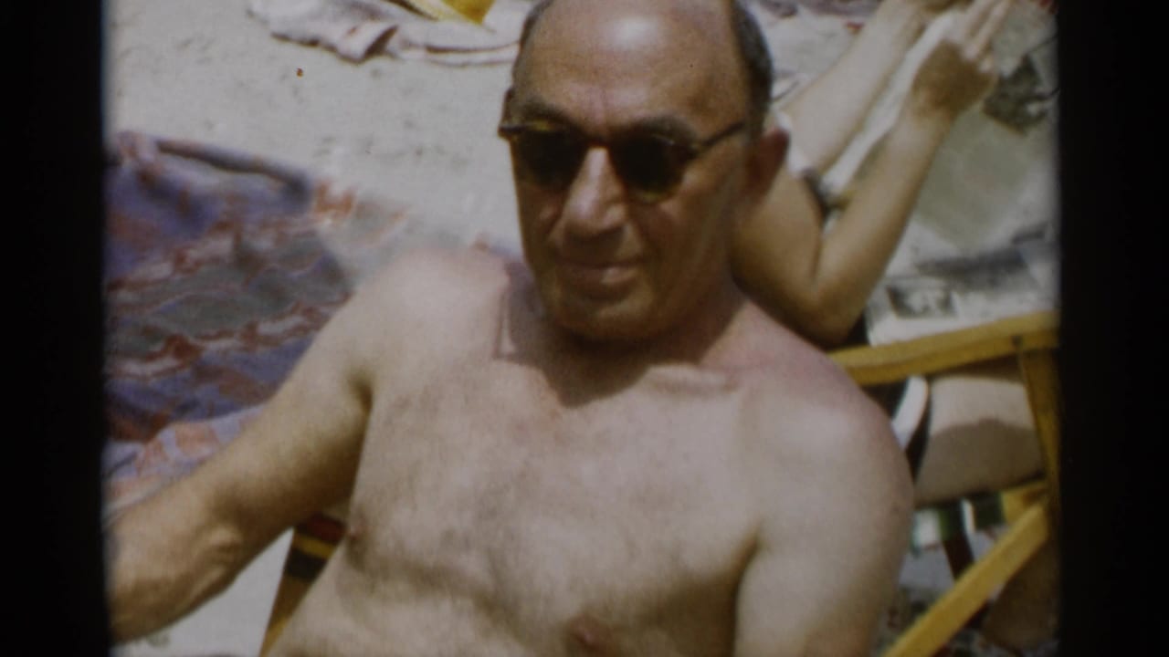Shirtless man in sunglasses reclining on a beach lounge chair.