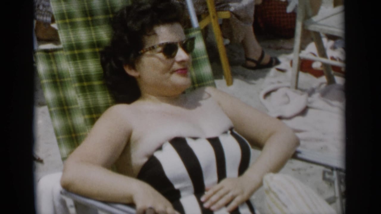 Woman in striped swimsuit reclines on a green plaid beach chair.