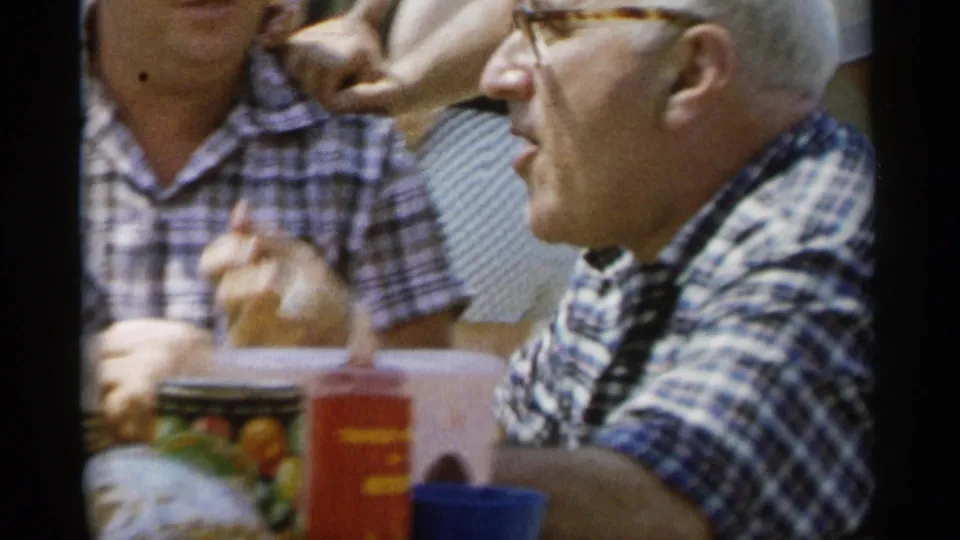 The Jones Beach home movie frames the man speaking or gesturing at the picnic table, with family members and food containers around him.