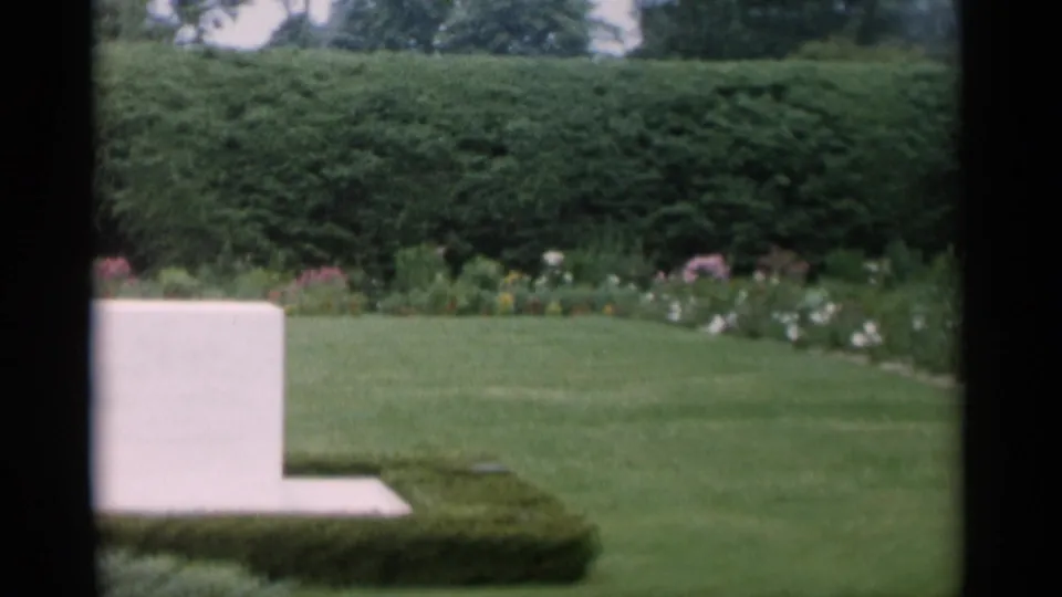 Garden pan across lawn and hedges at Jones Beach, with the white stone marker partly visible at the left edge.