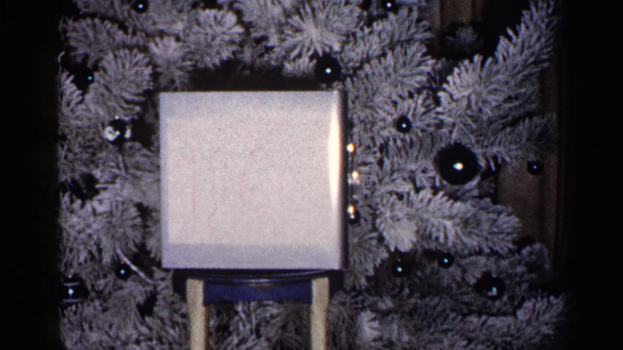 Similar view of a square object on a stand against a flocked tree and dark ornaments.