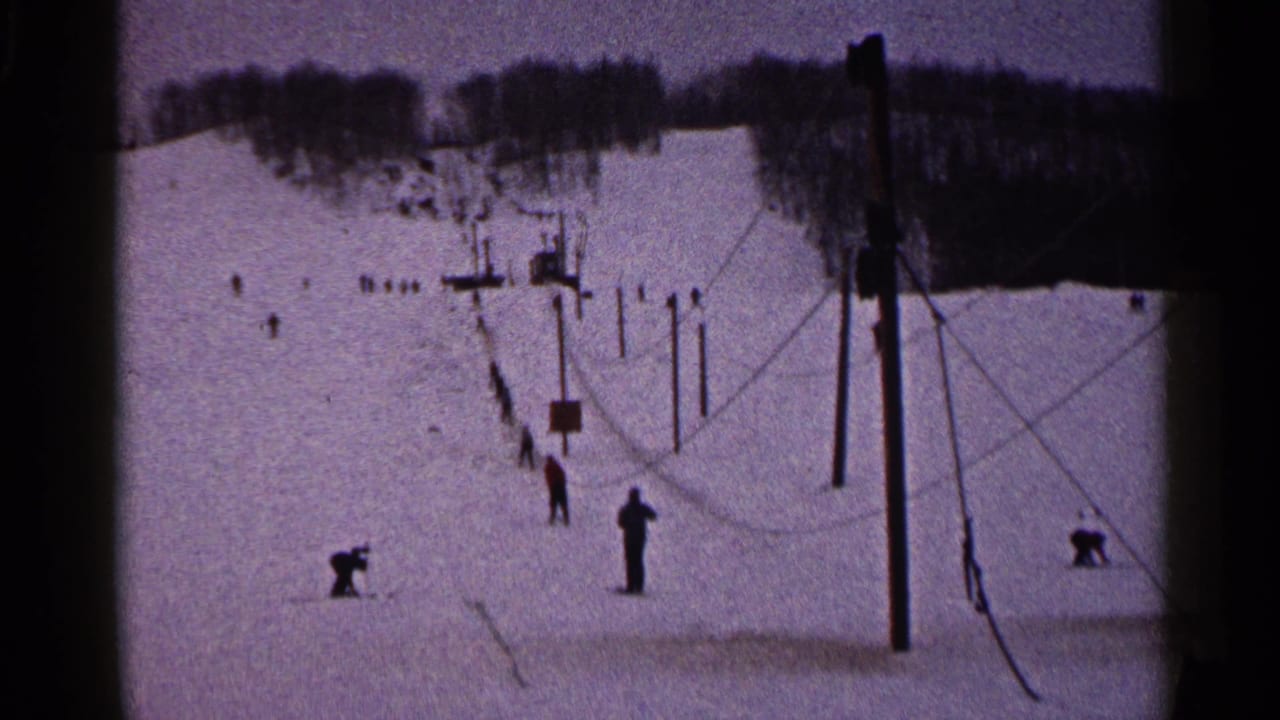 Scattered skiers stand and crouch near a ski lift line.